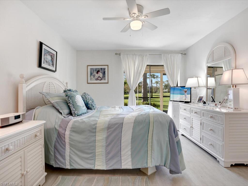 1232 Commonwealth Circle, Unit P102 Naples, FL 34116 - Photo 19 of 30 a bedroom with a large bed and a chandelier