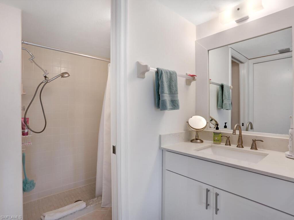 1232 Commonwealth Circle, Unit P102 Naples, FL 34116 - Photo 21 of 30 a bathroom with a sink and mirror with shower
