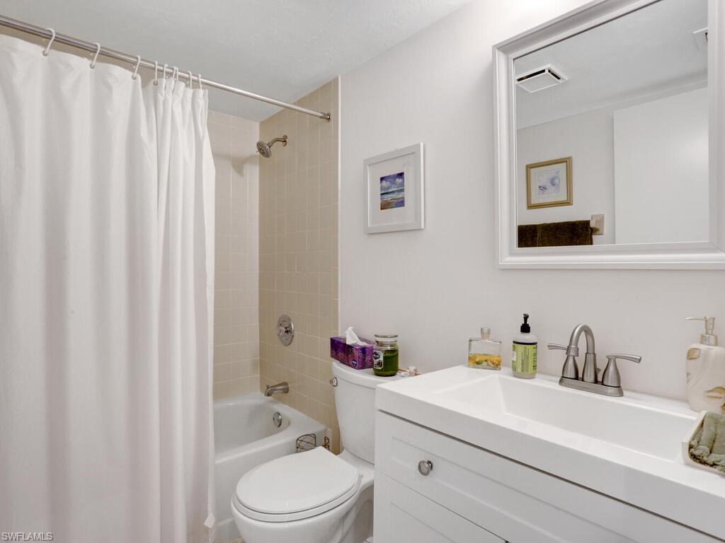 1232 Commonwealth Circle, Unit P102 Naples, FL 34116 - Photo 23 of 30 a bathroom with a sink a toilet and shower curtain
