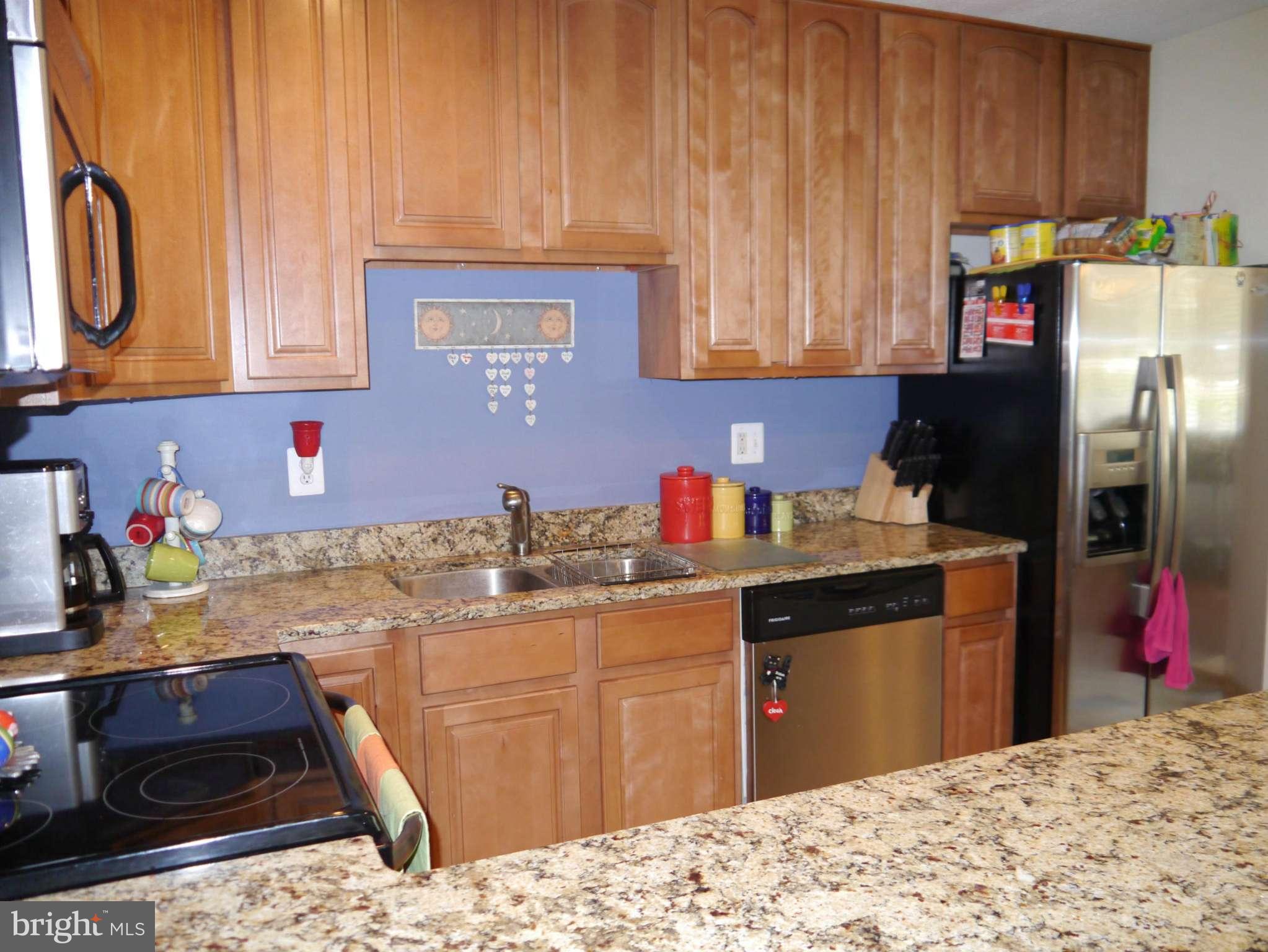 7412 Inzer Street Springfield, VA 22151 - Photo 10 of 27 a kitchen with stainless steel appliances kitchen island granite countertop a sink dishwasher stove and refrigerator with wooden cabinets