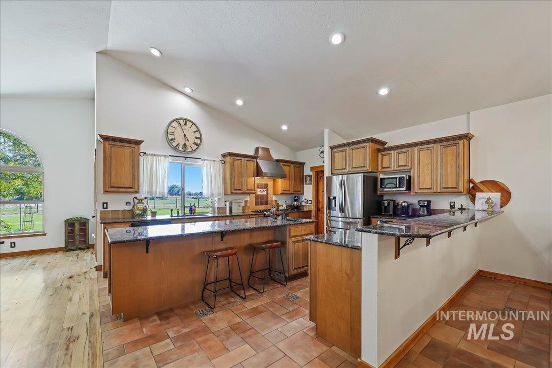 7639 Elko Lane Middleton, ID 83644 - Photo 12 of 47 Kitchen featuring a breakfast bar area, brown cabinets, dark stone countertops, recessed lighting, and appliances with stainless steel finishes