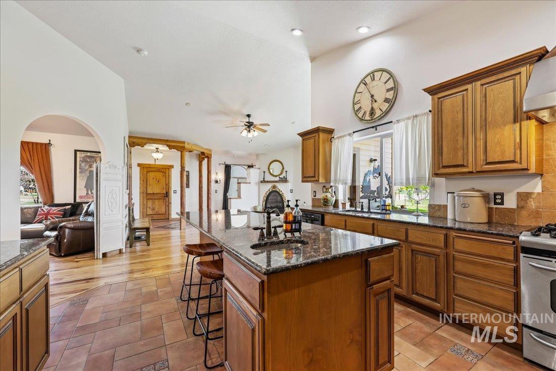 7639 Elko Lane Middleton, ID 83644 - Photo 14 of 47 Kitchen with brown cabinets, dark stone counters, a breakfast bar area, a ceiling fan, and recessed lighting