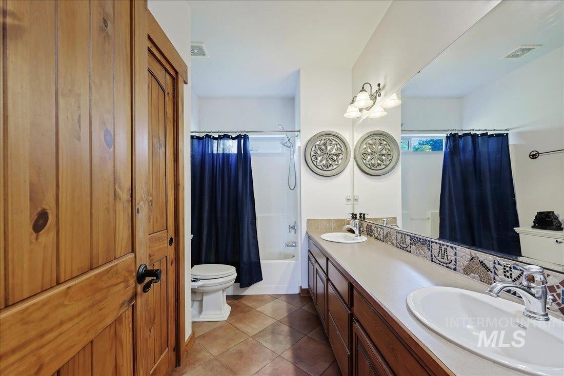 7639 Elko Lane Middleton, ID 83644 - Photo 28 of 47 Bathroom with shower / bath combo, dark tile patterned flooring, double vanity, and plenty of natural light