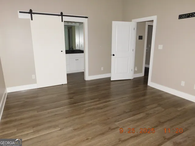 a view of an empty room with wooden floor and closet