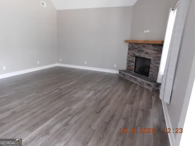 a view of an empty room with wooden floor and a fireplace
