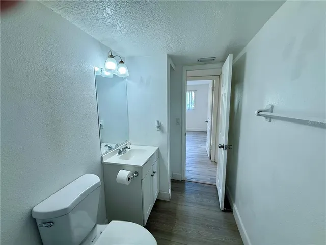 a bathroom with a granite countertop toilet a sink and a mirror