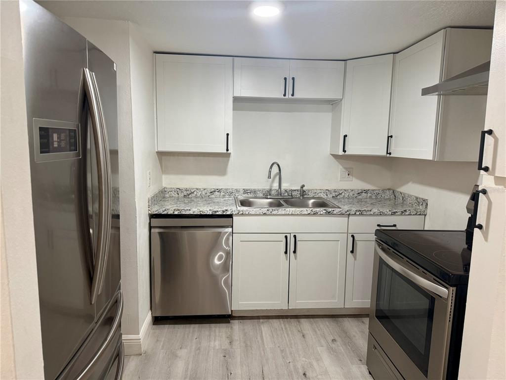 900 North Lake Destiny Road, Unit A Altamonte Springs, FL 32714 - Photo 3 of 26 a kitchen with stainless steel appliances granite countertop a refrigerator a stove and white cabinets with wooden floors
