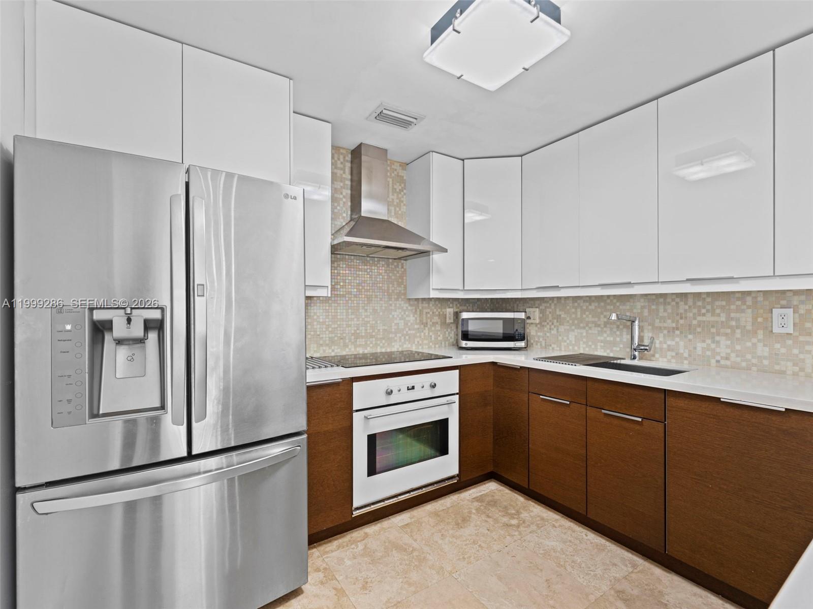 13404 Southwest 153 Terrace, Unit 2005 Miami, FL 33177 - Photo 20 of 49 a kitchen with stainless steel appliances granite countertop a refrigerator a sink dishwasher a stove and white cabinets with wooden floor