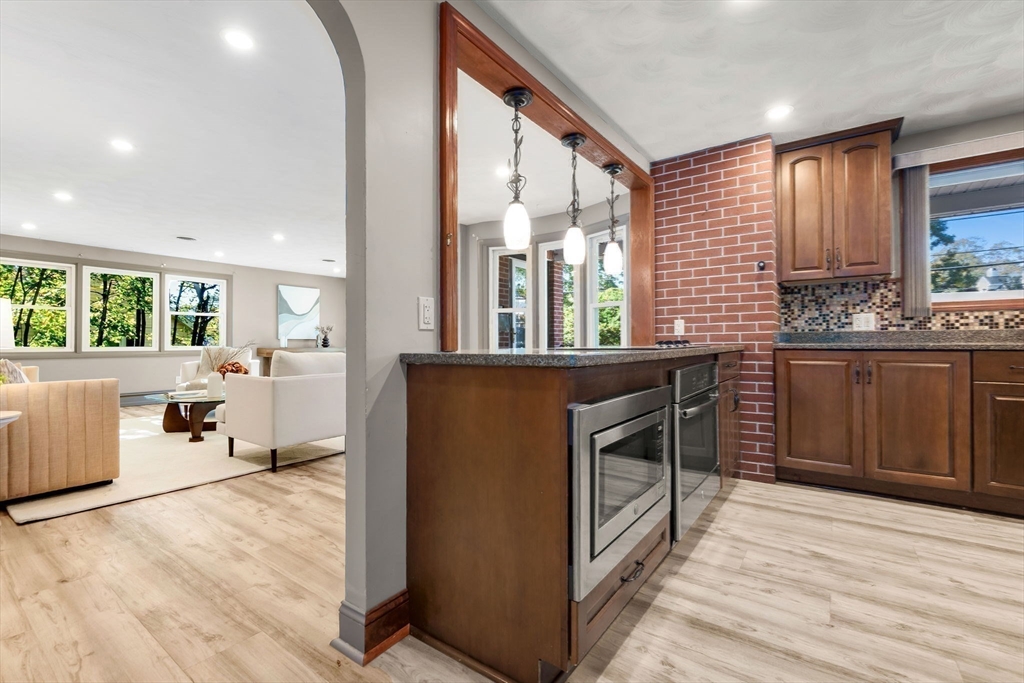 97 Oak Street Stoneham, MA 02180 - Photo 18 of 42 a kitchen with stainless steel appliances granite countertop a stove a sink dishwasher and a refrigerator with wooden floor