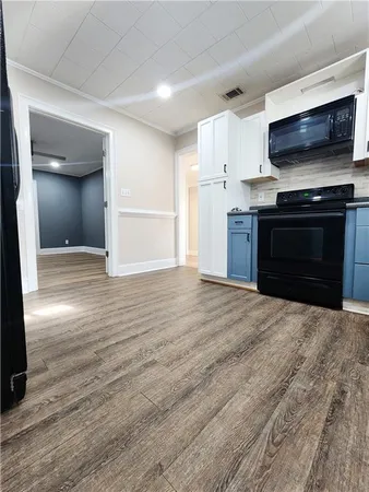 a view of kitchen and empty room with wooden floor