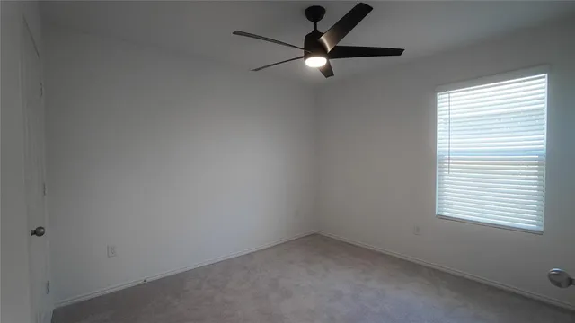 an empty room with a window and a fan
