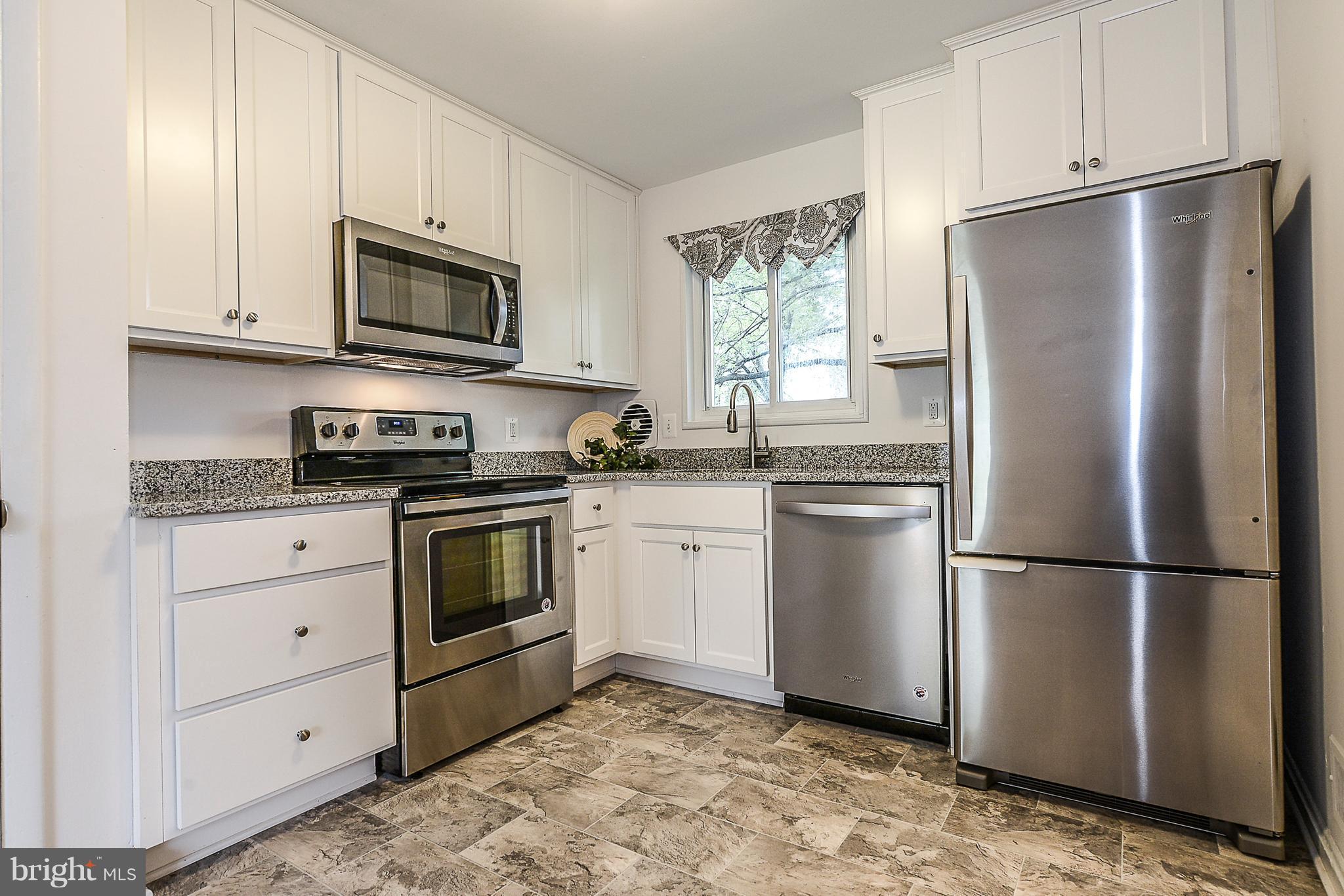 7106 Reservoir Road Springfield, VA 22150 - Photo 7 of 18 a kitchen with a refrigerator stove and white cabinets