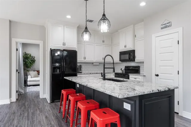 a kitchen with granite countertop kitchen island stainless steel appliances a sink stove refrigerator and cabinets