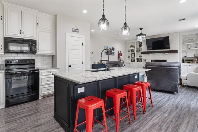 a kitchen with granite countertop a stove a sink and a microwave