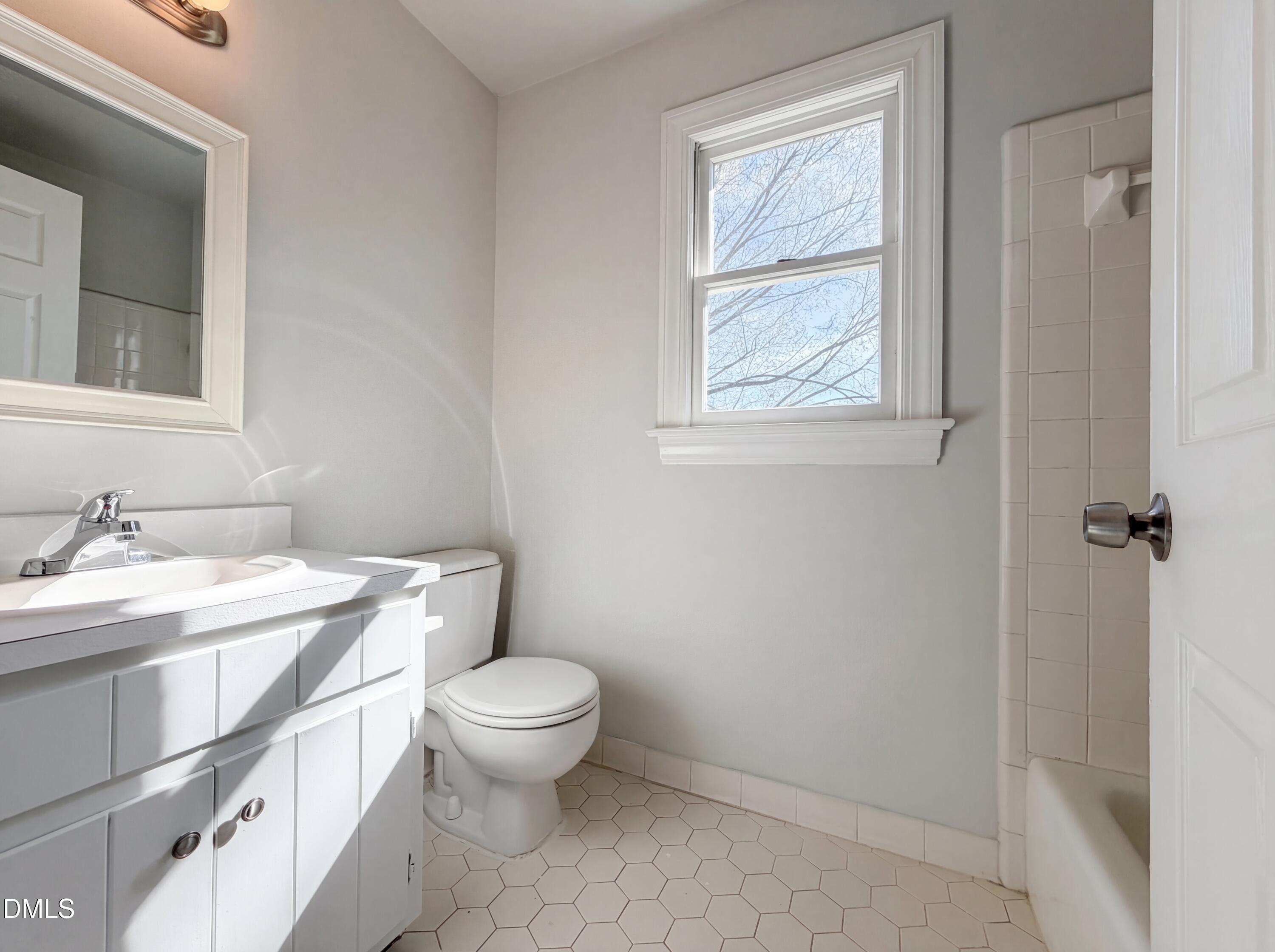 8612 Clovehitch Court Raleigh, NC 27615 - Photo 21 of 25 a bathroom with a granite countertop toilet a sink a mirror and a window