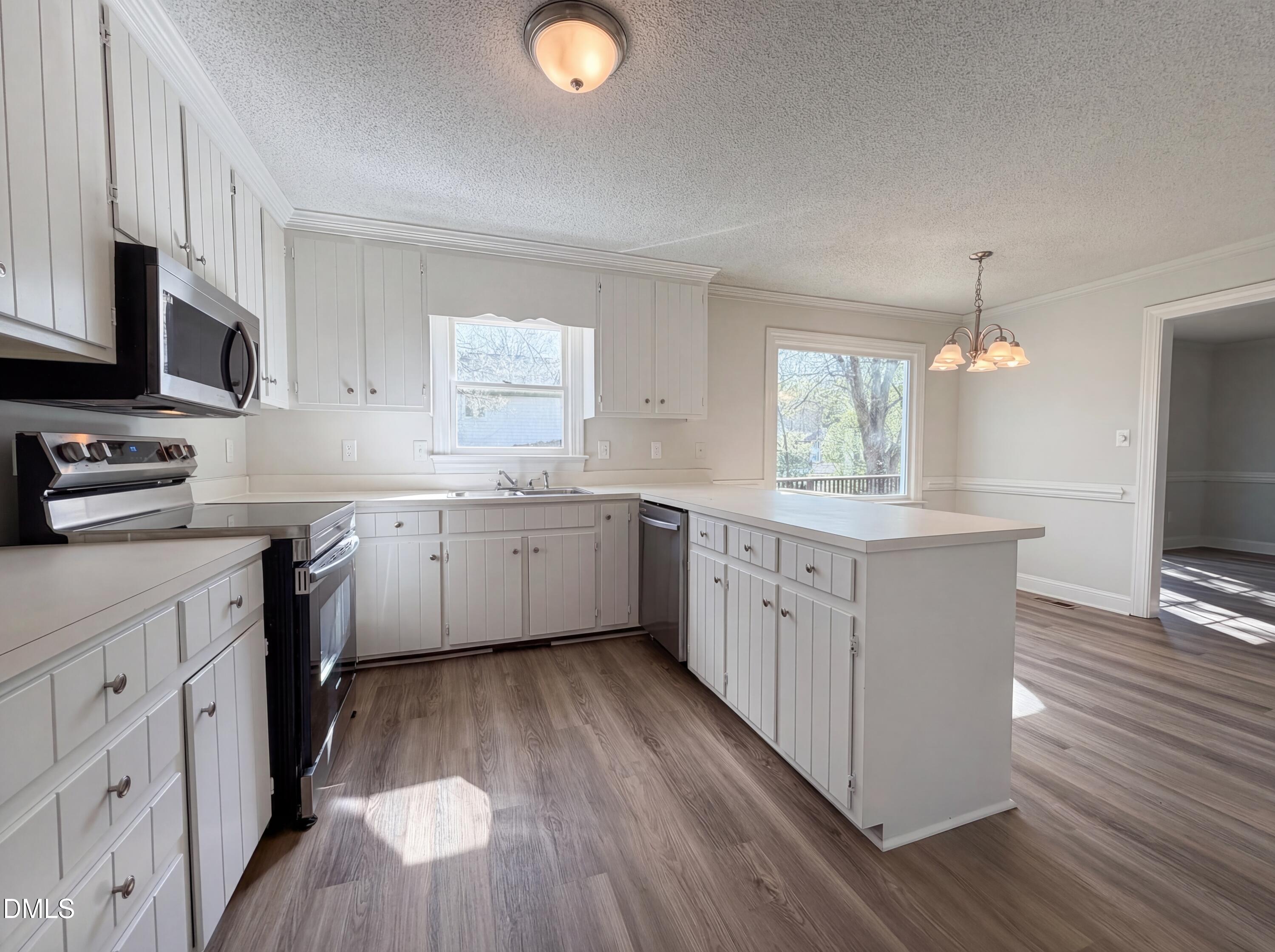 8612 Clovehitch Court Raleigh, NC 27615 - Photo 8 of 25 a kitchen with white cabinets a sink dishwasher and a stove with wooden floor