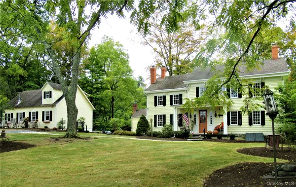 a view of a white house with a big yard and large trees