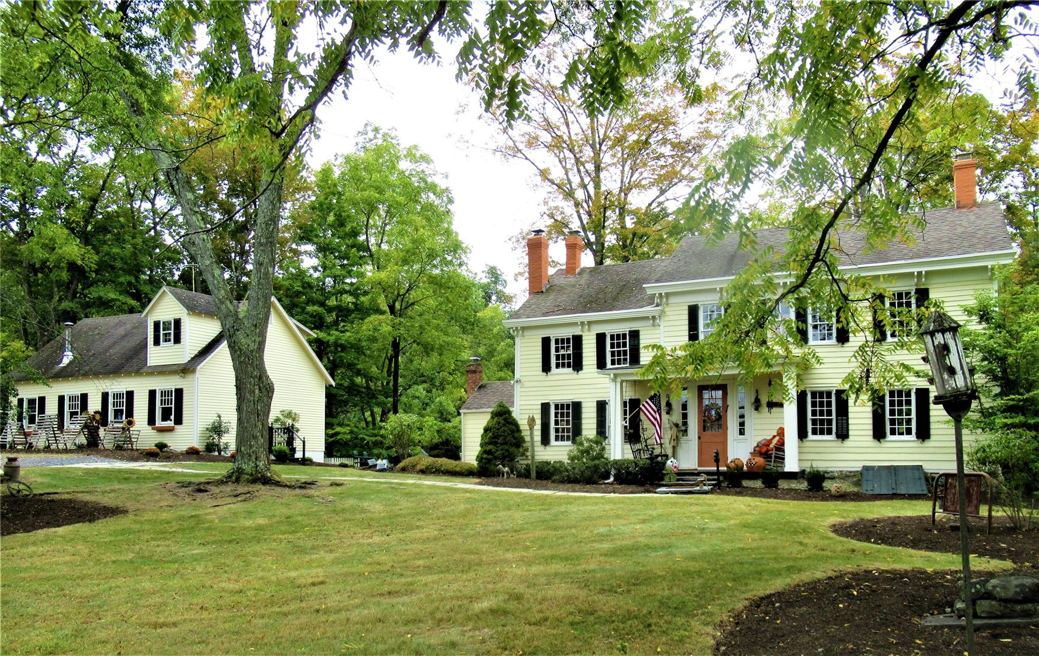 a view of a white house with a big yard and large trees
