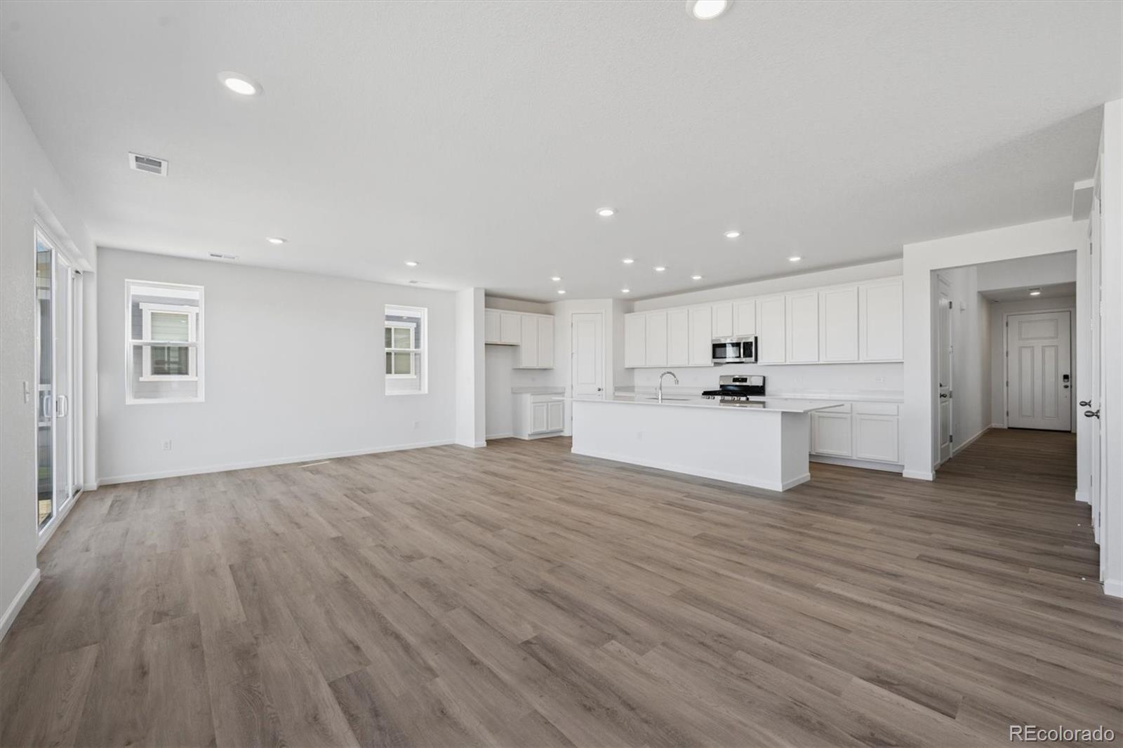 45935 Gentry Avenue Bennett, CO 80102 - Photo 8 of 22 a view of an empty room with wooden floor and a kitchen