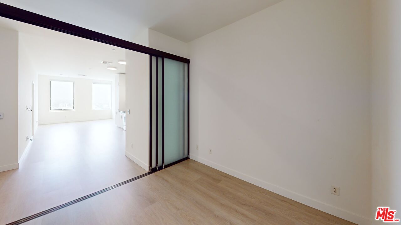 3810 Wilshire Boulevard, Unit 1108 Los Angeles, CA 90010 - Photo 11 of 15 an empty room with wooden floor and a window