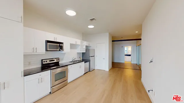 a kitchen with stainless steel appliances a refrigerator a sink a stove top oven and cabinets