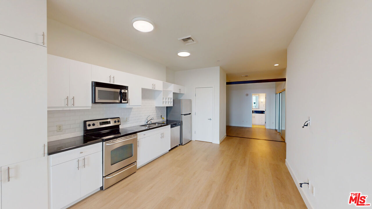 3810 Wilshire Boulevard, Unit 1108 Los Angeles, CA 90010 - Photo 3 of 15 a kitchen with stainless steel appliances a refrigerator a sink a stove top oven and cabinets