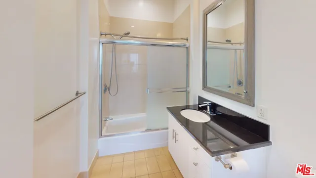 a bathroom with a granite countertop sink a mirror and shower