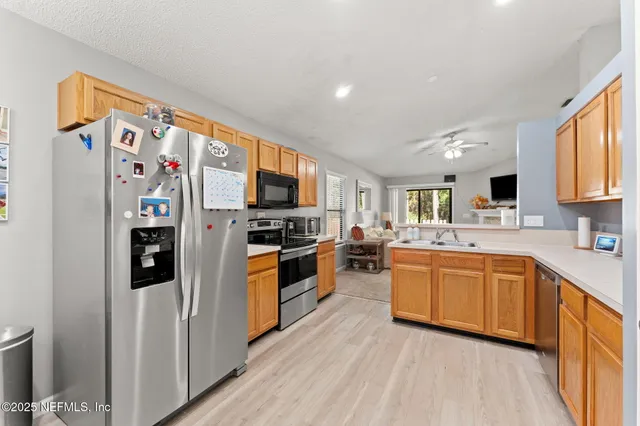 a large kitchen with stainless steel appliances granite countertop a refrigerator and a stove top oven