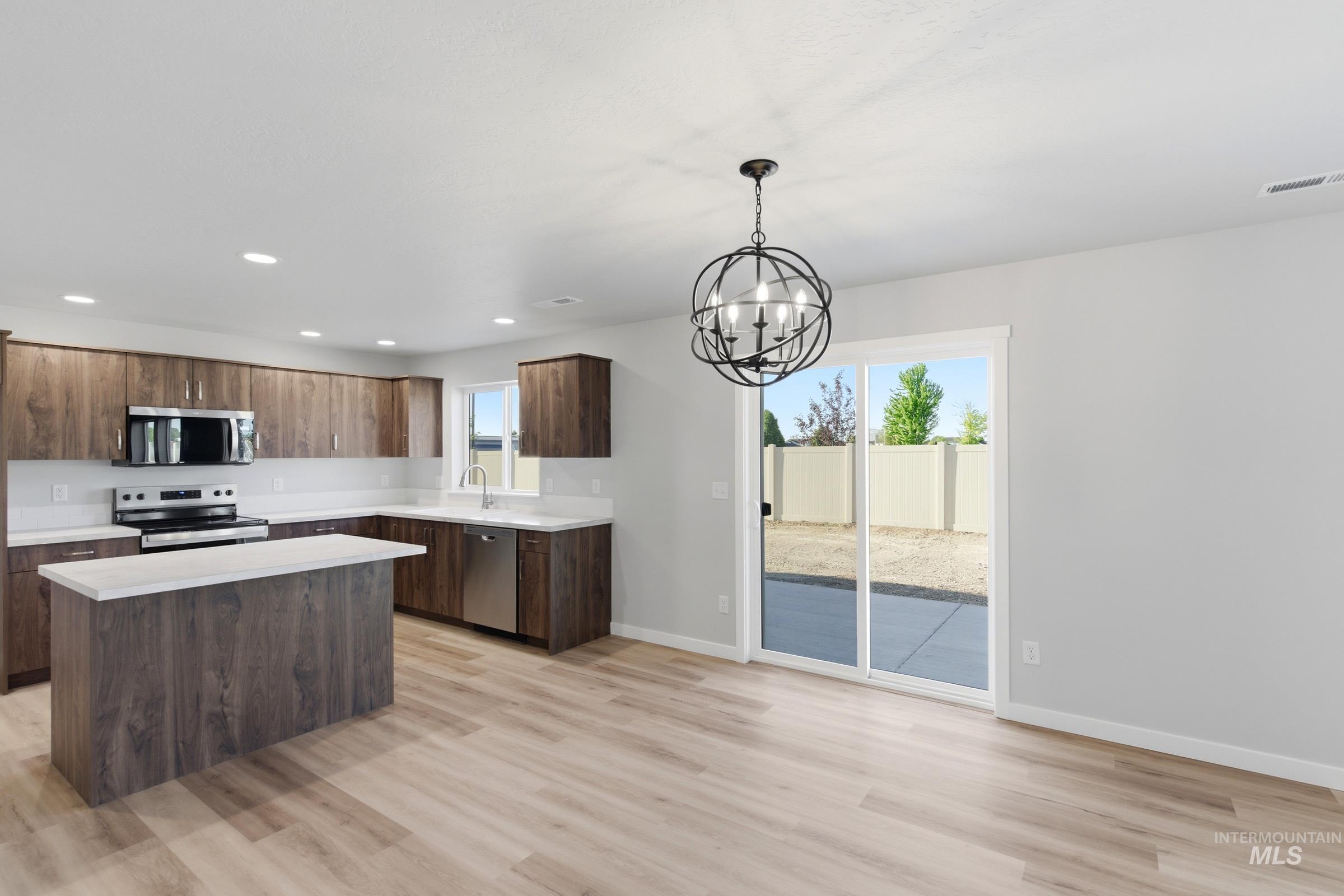 13709 Redway Court Caldwell, ID 83607 - Photo 6 of 28 Open-concept living area featuring light wood-finish flooring and a contemporary orb chandelier
