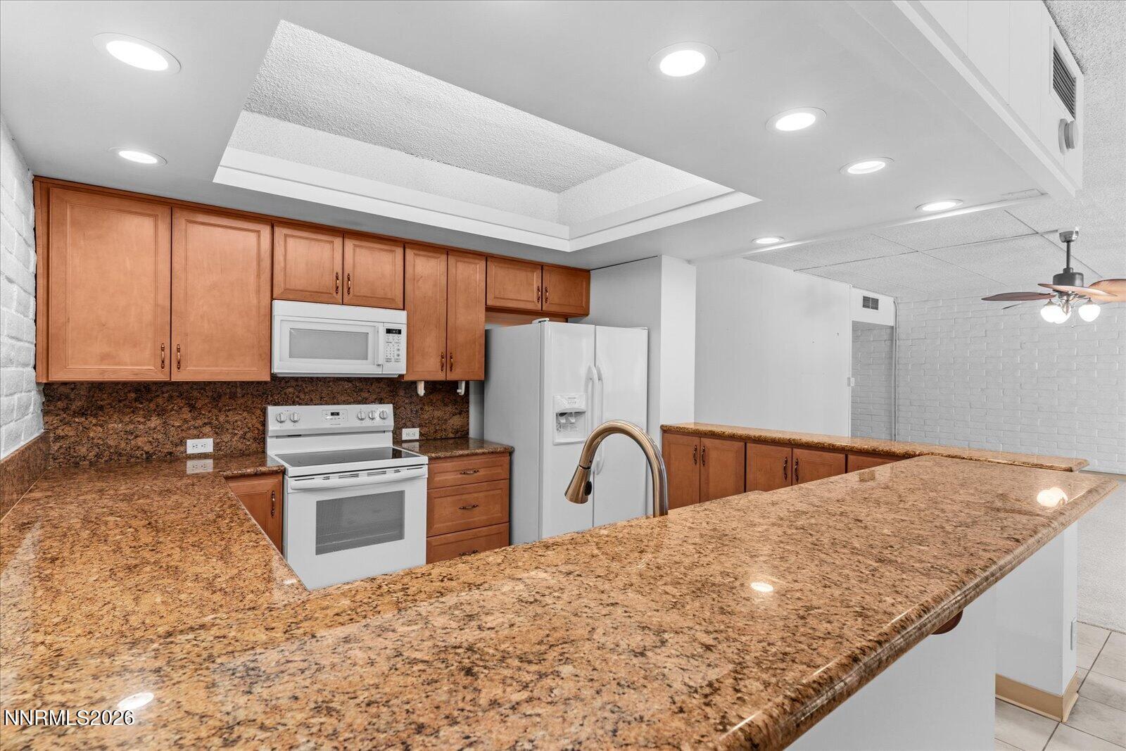 1200 Riverside Drive, Unit 1229 Reno, NV 89503 - Photo 25 of 51 a kitchen with stainless steel appliances granite countertop a sink a stove a refrigerator cabinets and a dining table
