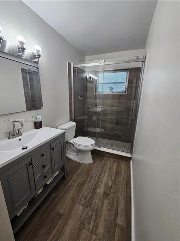 a bathroom with a sink a toilet a mirror and shower