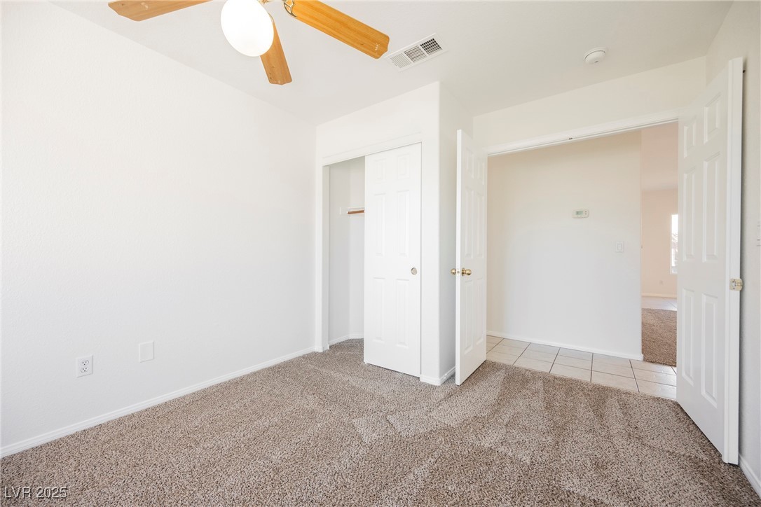 179 Grayce Mesquite, NV 89027 - Photo 16 of 25 Unfurnished bedroom with light colored carpet, a closet, light tile patterned flooring, and a ceiling fan