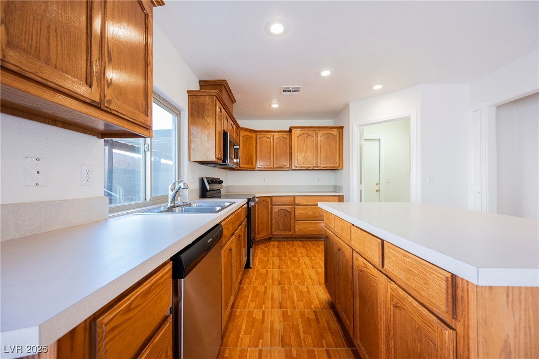 179 Grayce Mesquite, NV 89027 - Photo 2 of 25 Kitchen with brown cabinetry, stainless steel appliances, light countertops, recessed lighting, and light wood-style floors