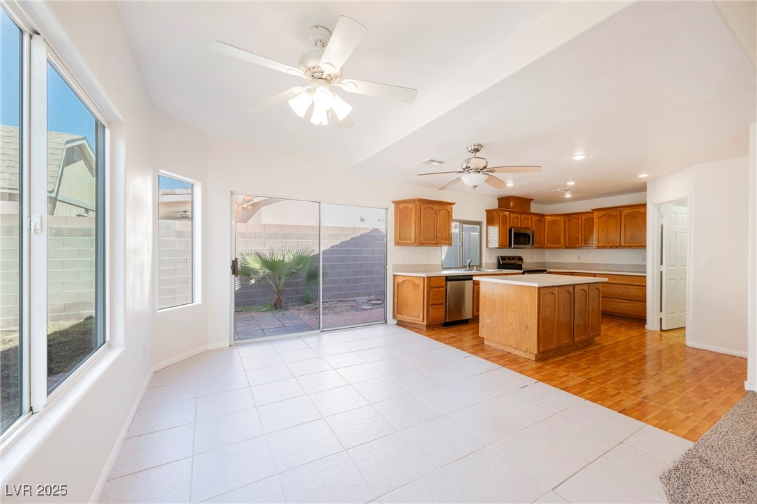 179 Grayce Mesquite, NV 89027 - Photo 3 of 25 Kitchen featuring light countertops, light tile patterned flooring, stainless steel appliances, a kitchen island, and brown cabinetry