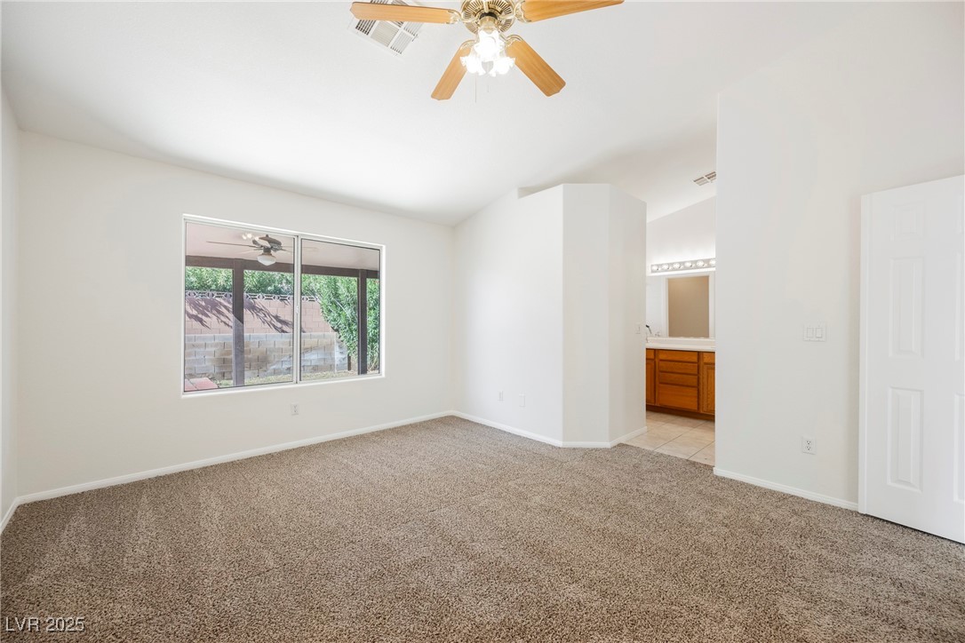 179 Grayce Mesquite, NV 89027 - Photo 6 of 25 Unfurnished bedroom with light carpet, vaulted ceiling, ensuite bathroom, and ceiling fan