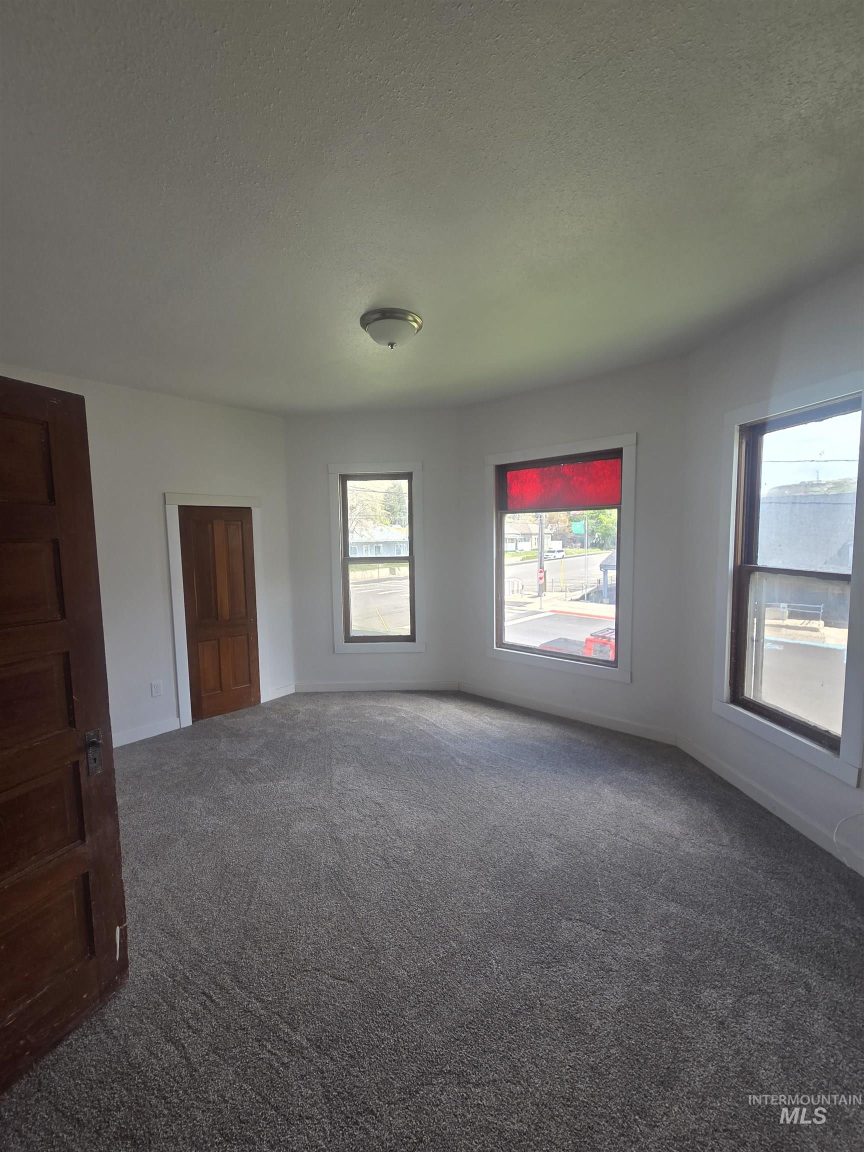 986 Columbia Street Pomeroy, WA 99347 - Photo 14 of 20 Spacious room featuring gray carpet, white walls, multiple windows, and a ceiling-mounted light fixture