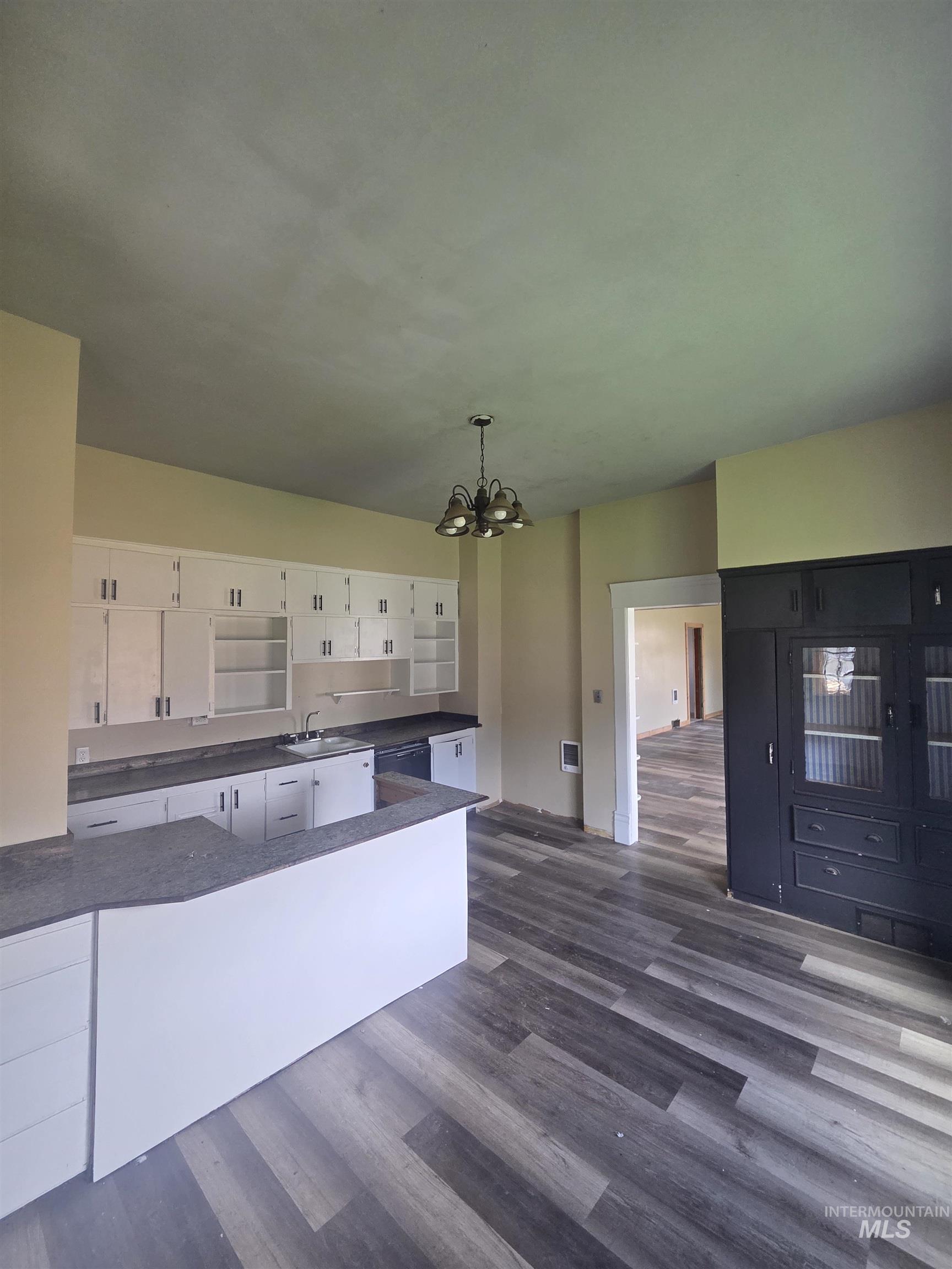 986 Columbia Street Pomeroy, WA 99347 - Photo 18 of 20 Kitchen space featuring wood-finish flooring, white cabinetry, dark countertops, and a built-in breakfast bar