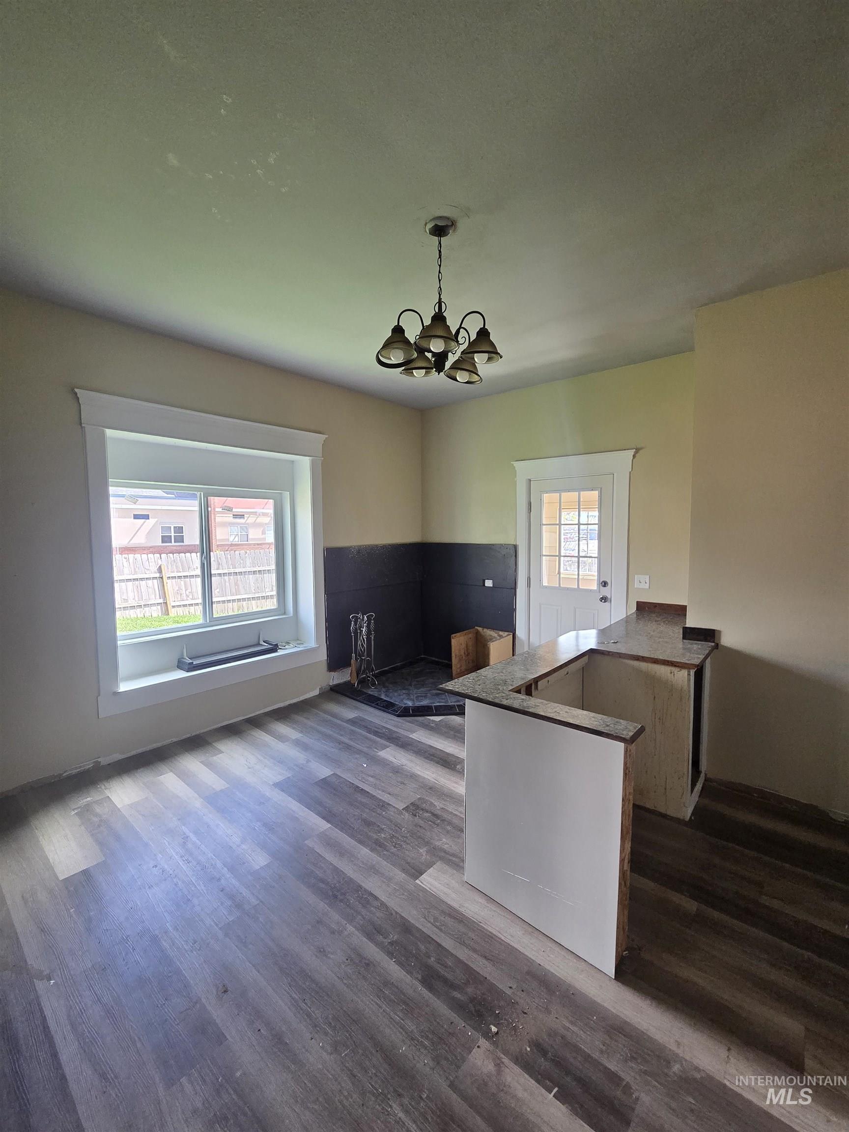 986 Columbia Street Pomeroy, WA 99347 - Photo 19 of 20 Spacious area featuring wood-finish flooring, a contemporary chandelier, a window with white trim, and a partial bar with a countertop