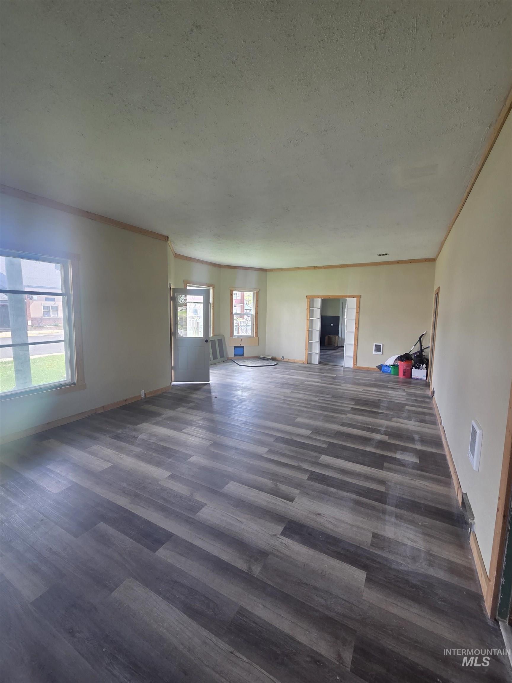 986 Columbia Street Pomeroy, WA 99347 - Photo 4 of 20 Spacious interior featuring wide-plank wood-finish flooring, light-toned walls, multiple windows, and a doorway opening to an additional room