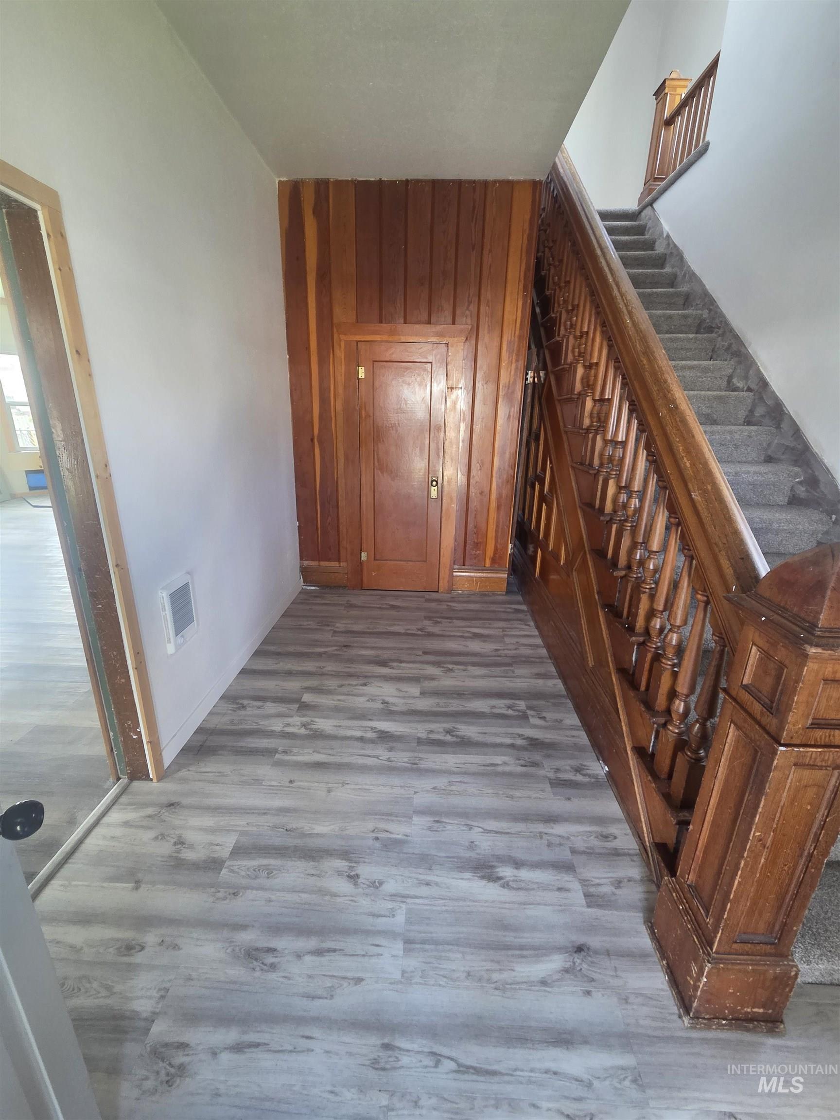 986 Columbia Street Pomeroy, WA 99347 - Photo 7 of 20 Entryway featuring wood-finish flooring, a wood paneled wall, and a staircase with a carved wood banister
