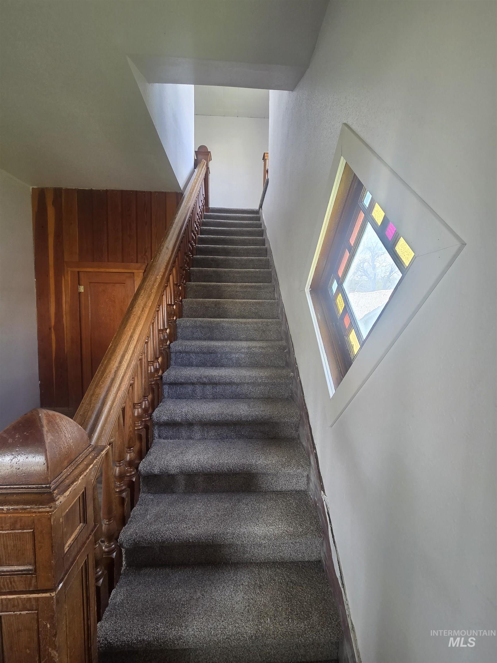 986 Columbia Street Pomeroy, WA 99347 - Photo 8 of 20 Carpeted staircase with an ornate wood-spindled banister and a decorative stained-glass window