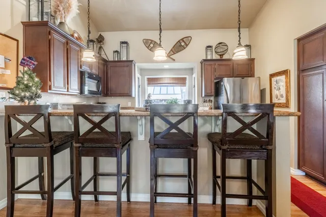 a kitchen with stainless steel appliances granite countertop a dining table chairs refrigerator and sink