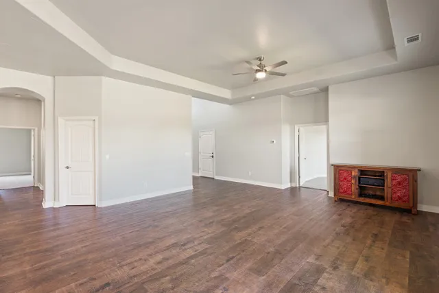 an empty room with wooden floor and ceiling fan