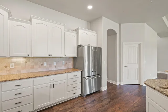 a kitchen with granite countertop white cabinets and stainless steel appliances