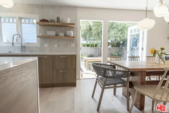 a kitchen with stainless steel appliances granite countertop a table chairs in it and wooden floors