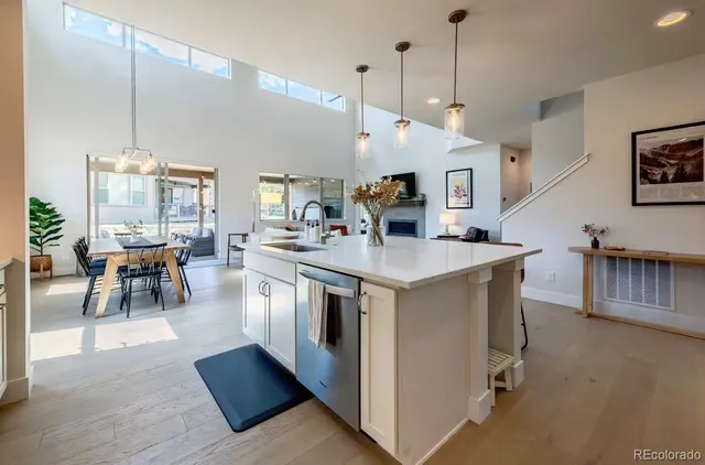 a open kitchen with stainless steel appliances granite countertop a stove oven a dining table and chairs with wooden floor