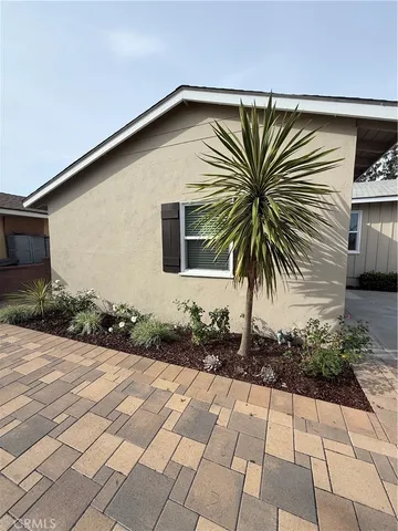 a front view of a house with a yard and potted plants