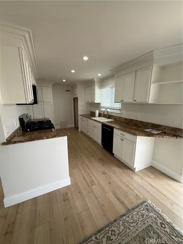 a large kitchen with stainless steel appliances granite countertop a stove a sink dishwasher and a refrigerator with wooden floors