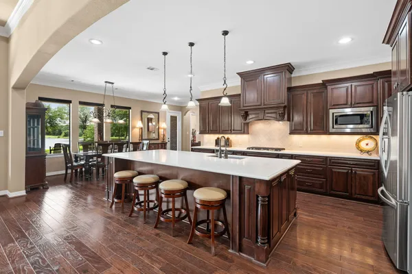 a kitchen with stainless steel appliances granite countertop a table chairs and a wooden floor