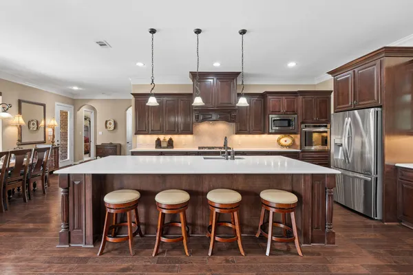 a kitchen with stainless steel appliances granite countertop a table chairs sink refrigerator and microwave